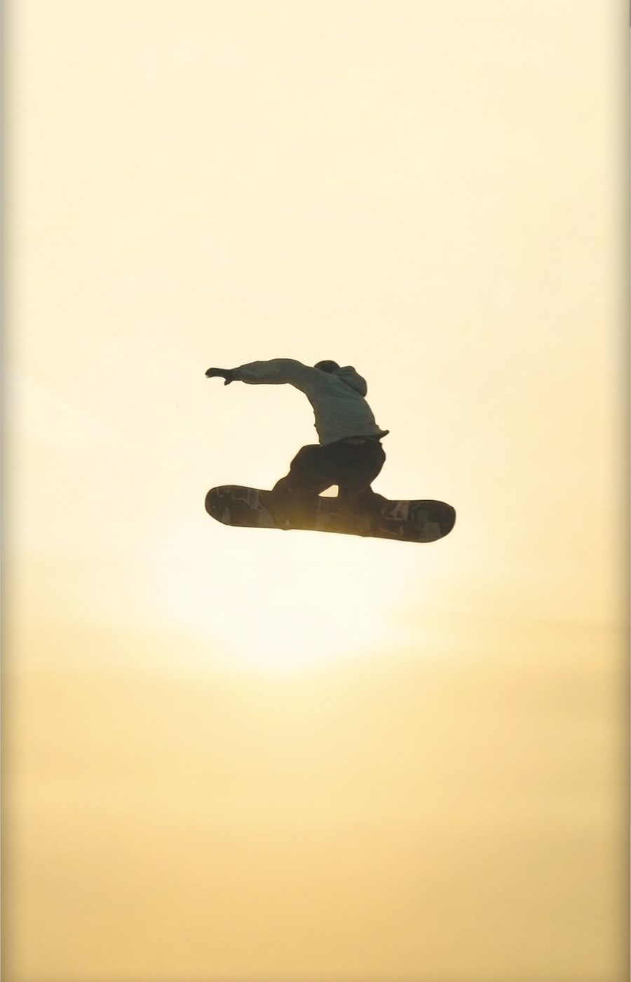 Snowboarder silhouette mid-air at sunset